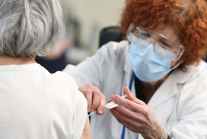 A woman is vaccinated at Olympic Stadium in Montreal on Monday. Canadians on the coasts and Quebec were most optimistic about their provinces rollout plans, according to a survey.