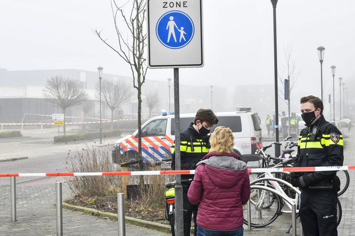 Police officers speak with a pedestrian as they close off a street after an explosion occurred near a Covid-19 test centre, shattering windows but causing no apparent injuries, in Bovenkarspel, the Netherlands, on March 3, 2021.