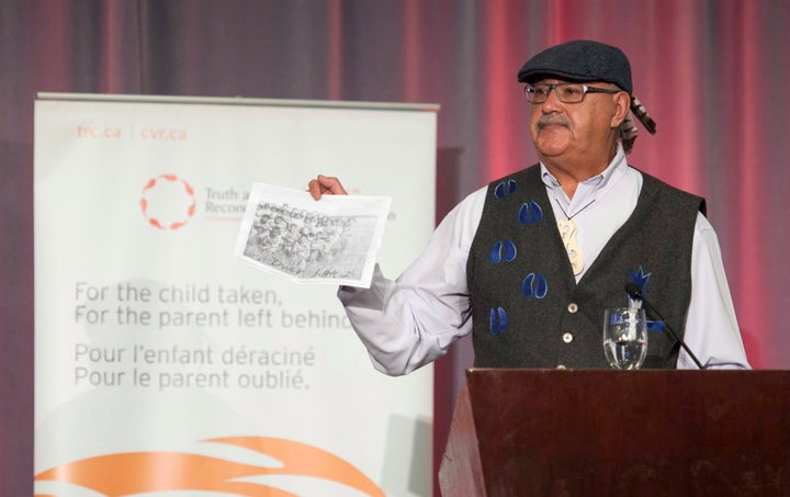 Residential school survivor Eugene Arcand holds up a picture of his classmates at the release of the final report of the Truth and Reconciliation commission on Dec. 15, 2015.