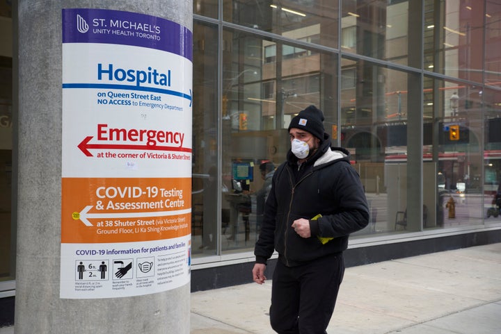 A man wearing a protective face mask walks past St. Michael's Hospital in Toronto on Jan. 11, 2021, amid the ongoing COVID-19 pandemic.