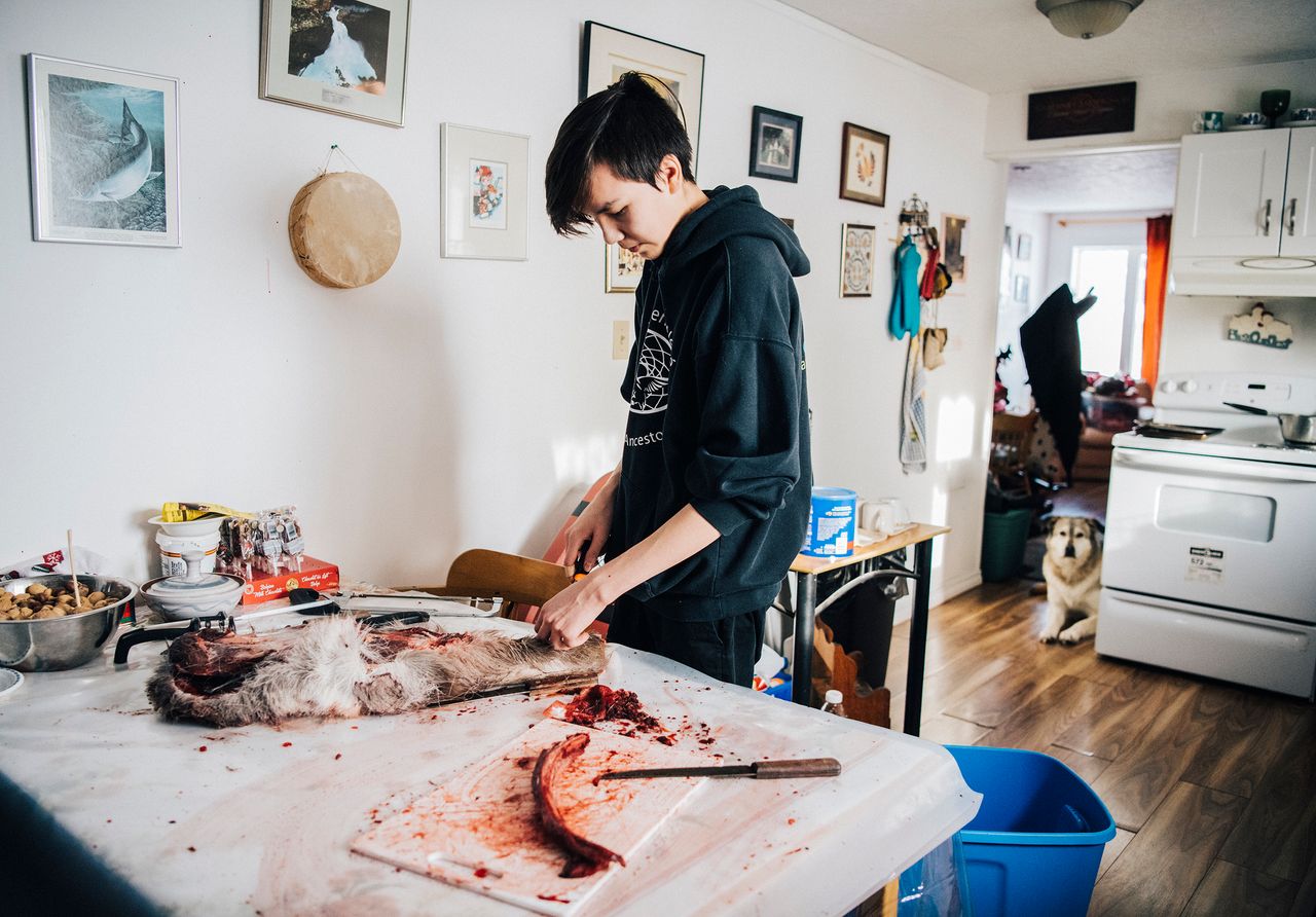 Iris’s son Tanner cuts up caribou meat at his grandmother’s home.