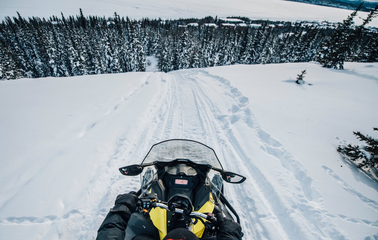 Going down a large hill on the back of a snowmobile in the Thaidene Nëné Indigenous Protected Area.