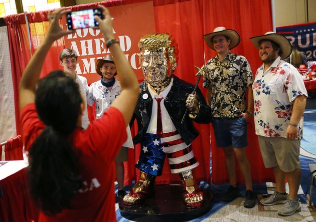 Plusieurs personnes posent avec une statue de l'ancien président américain Donald Trumpà la 