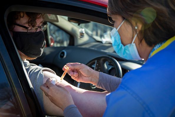 A patient receives their first dose of the COVID-19 AstraZeneca Oxford vaccine in their arm while attending the drive through vaccination centre in the car park of Folkestone council offices