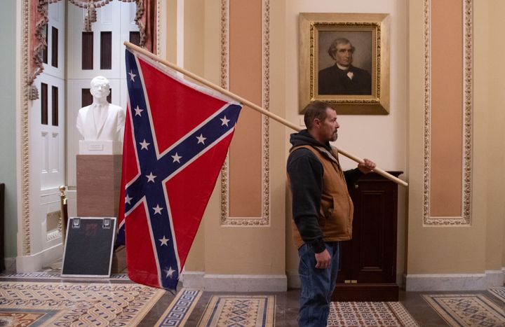 Kevin Seefried holds a Confederate flag outside the Senate on Jan. 6. He stormed the Capitol with his son, Hunter.