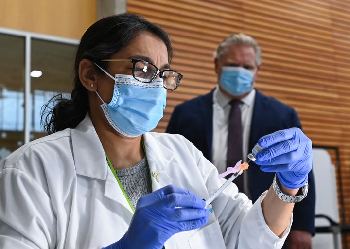 Ontario Premier Doug Ford, right, watch a health-care work fill a vial with the coronavirus vaccine as he tours a mass COVID-19 vaccination clinic for Peel Region in Mississauga, Ont., on March 1, 2021.