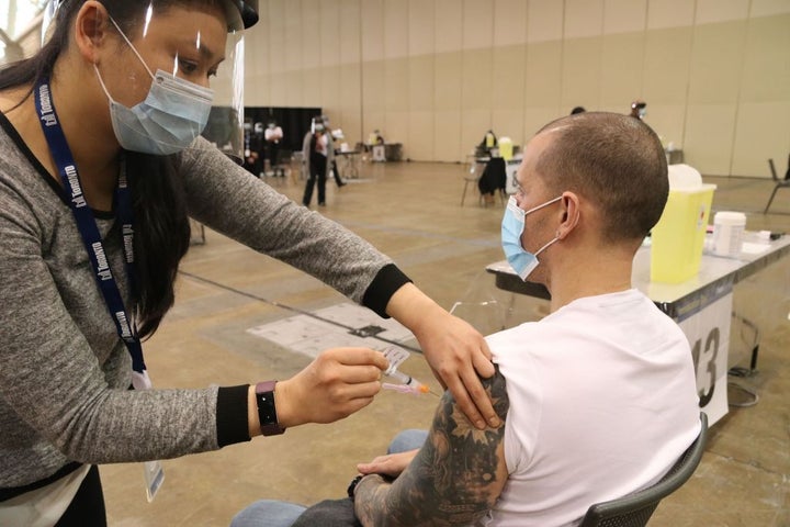 A man wearing a face mask receives a dose of COVID-19 vaccine at an immunization clini in Toronto on Jan. 18, 2021.