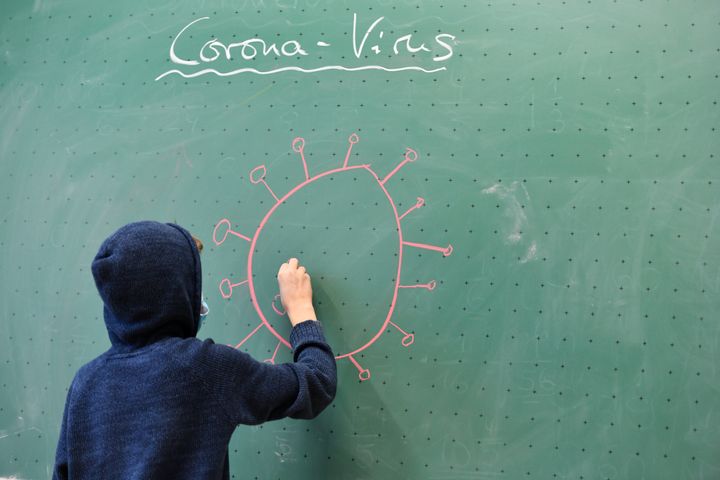 Un niño dibuja en la pizarra el coronavirus.