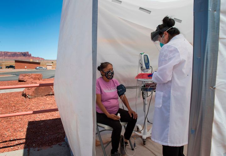 A nurse checks the vitals of a Navajo Indian woman at a COVID-19 testing center at the Navajo Nation town of Monument Valley in Arizona on May 21, 2020. Monument Valley would normally be teeming with tourists at this time of year -- instead it's become the latest COVID-19 hotspot inside the hard-hit Navajo Nation, America's biggest Native American territory.