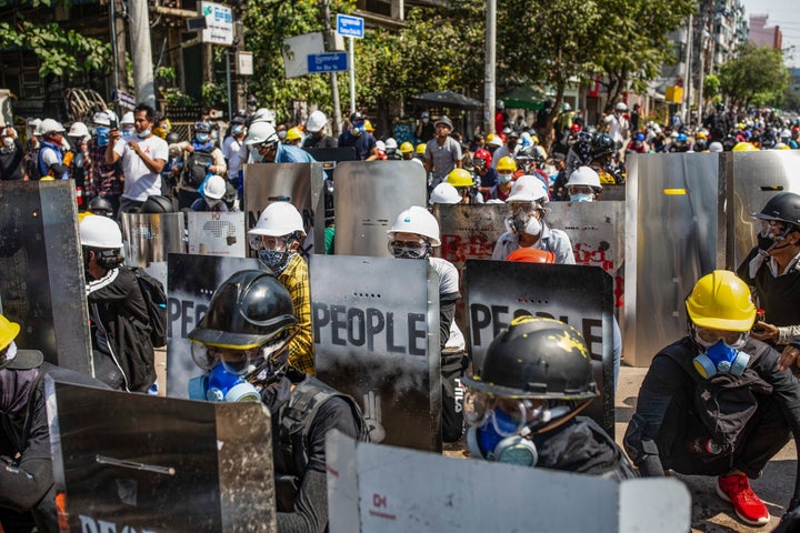 Anti-coup protesters protect themselves on Monday behind makeshift shields during a demonstration against the takeover of the