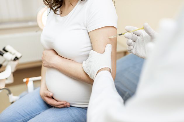 A pregnant woman receives a vaccine injection.