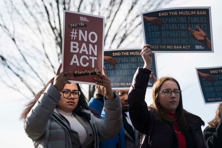 People hold signs showing their support of ending a travel ban on Muslim-majority countries outside the U.S. Capitol on Jan. 27, 2020. (Photo by Sarah Silbiger/Getty Images)