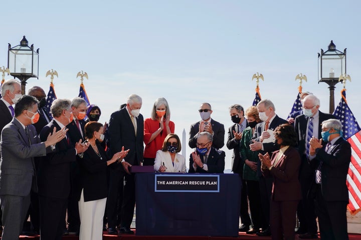 House Speaker Nancy Pelosi signs the American Rescue Plan as Senate Majority Leader Chuck Schumer and others applaud during the enrollment ceremony following passage of the bill.