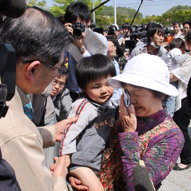 福島県飯舘村で、計画的避難のために村を離れる住民に声をかける菅野典雄村長（左）