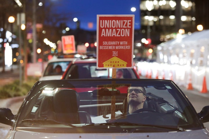 A man holds a sign in support of Amazon workers unionizing in Bessemer, Alabama, during a Tax Amazon Car Caravan and Bike Bri