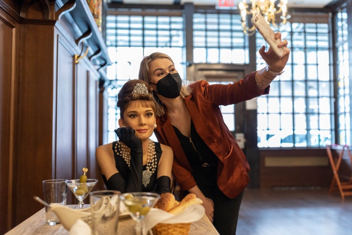 A patron snapping a photo with a wax figure of Audrey Hepborn at Peter Luger's Steakhouse in Brooklyn in March 2021.