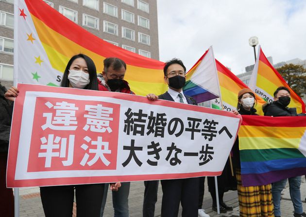 Des militants brandissent le drapeau arc-en-ciel devant la court de justice de Sapporo (Hokkaido), ce 17 mars 2021. (STR / JIJI PRESS / AFP)