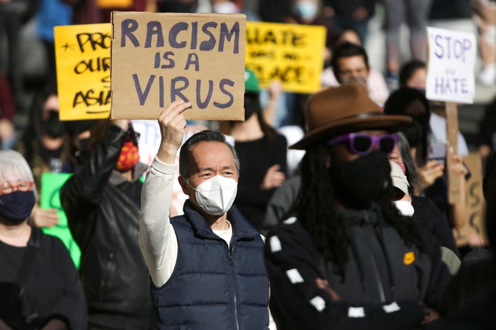 A man holds a sign that reads "Racism is a Virus" during the "We Are Not Silent" rally against anti-Asian hate in response to recent anti-Asian crime in the Chinatown-International District of Seattle, Washington, on March 13.