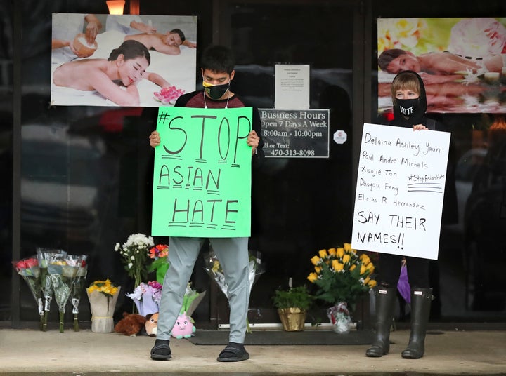 After dropping off flowers Jesus Estrella, left, and Shelby stand in support of the Asian and Hispanic community outside Youn