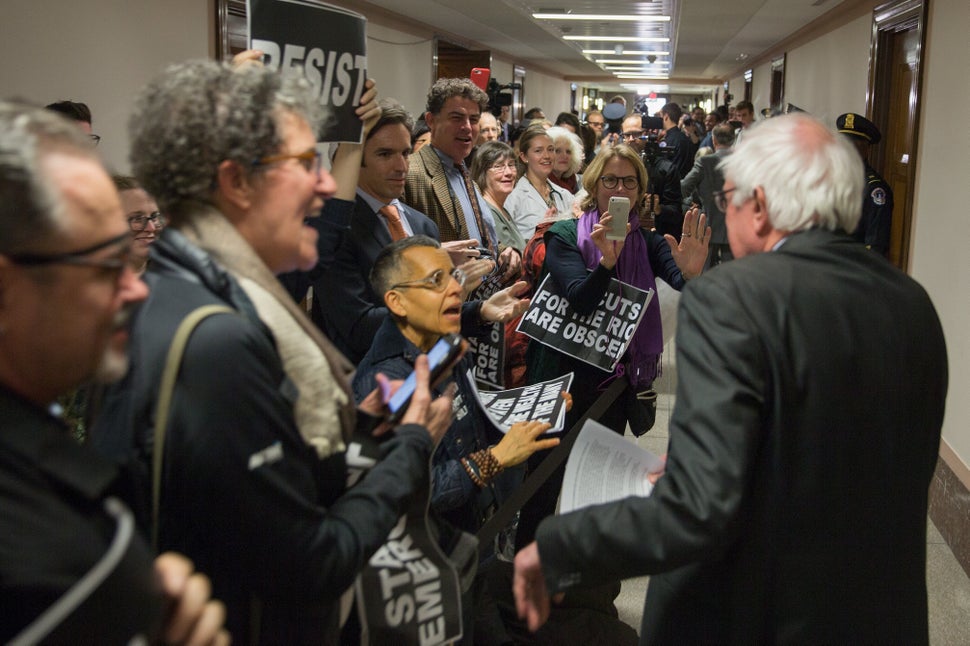 Demonstrators greet Sen. Bernie Sanders on his way to the full committee markup of GOP tax cut legislation in November 2017. 