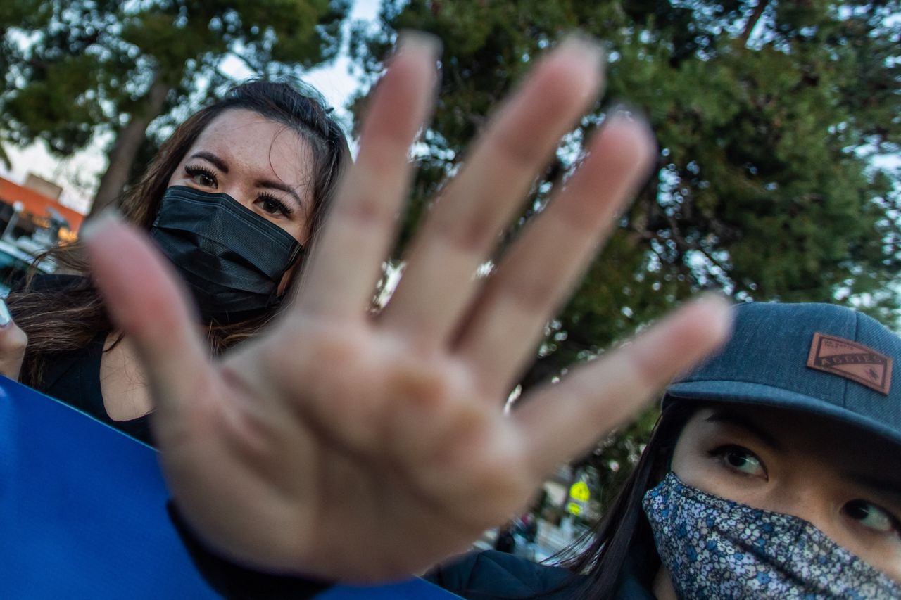 Clover and Julie Tran stand with outstretched hands during a candlelight vigil in Garden Grove, California, on March 17, 2021, to unite against the recent spate of violence targeting Asians.