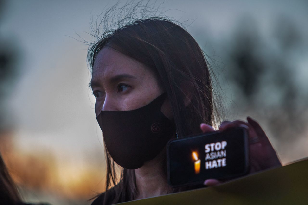 A woman holds her phone, featuring the message "Stop Asian Hate," during a candlelight vigil in Garden Grove, California, on March 17, 2021.