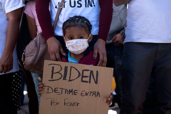 Dareli Matamoros, a girl from Honduras, holds a sign asking President Biden to let her in during a migrant demonstration dema