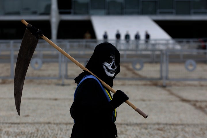 Un manifestante disfrazado de muerto y vistiendo una faja presidencial simulada camina fuera del palacio presidencial de Planalto durante una prot