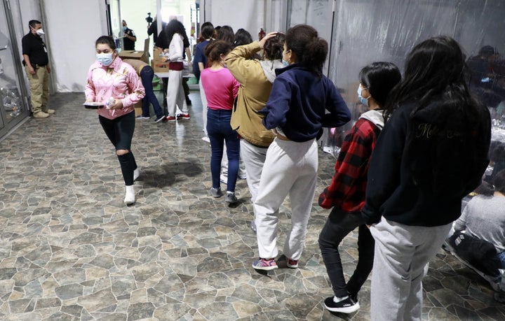 Children in temporary processing facilities in Donna, Texas, line up for food and drink.