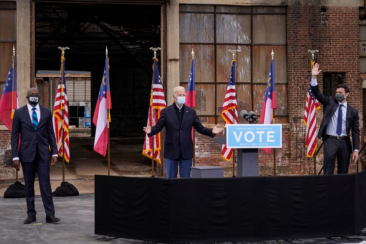 Flanked by U.S. Democratic Senate candidates Rev. Raphael Warnock (left) and Jon Ossoff (right), President-elect Joe Biden gestures to the crowd at the end of a drive-in rally at Pullman Yard on December 15, 2020 in Atlanta, Georgia.