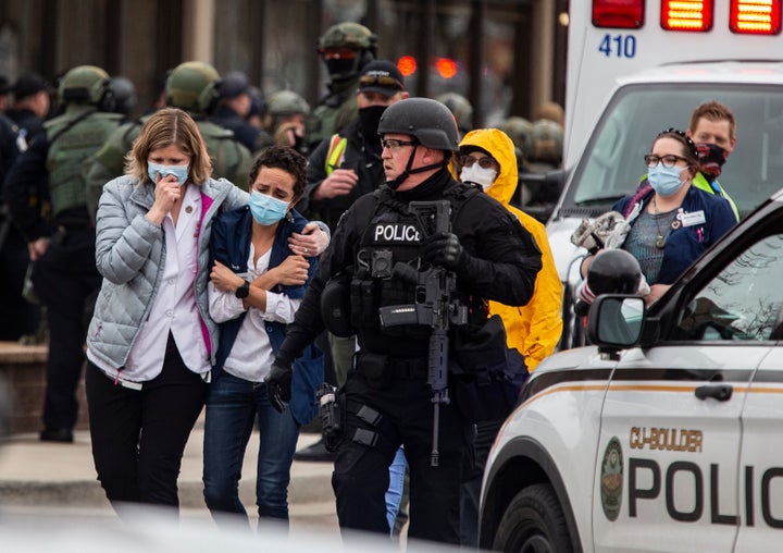 Health care workers walk out of King Soopers grocery store after a gunman opened fire at the store Monday, killing 10 people.