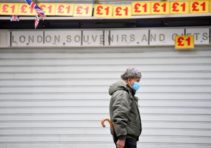 A pedestrian wearing a face covering walks past a souvenir shop, closed due to Covid-19, in central London on March 24