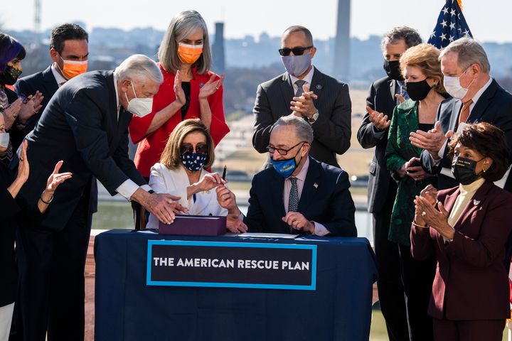 Speaker of the House Nancy Pelosi (D-Calif.) and Senate Majority Leader Chuck Schumer (D-N.Y.), center, sign the American Rescue Plan Act at a bill enrollment ceremony after the House passed the $1.9 trillion COVID-19 relief package on March 10.