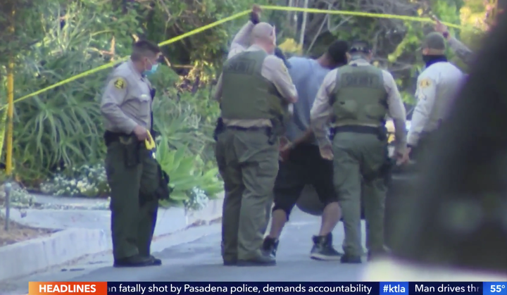 Robert Cotton is seen being taken into custody outside of a Los Angeles County house where authorities said two people were f
