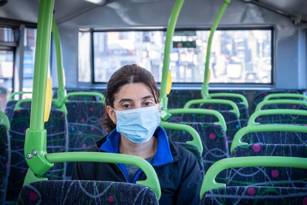 A commuter on her way to work using a face mask on a double-decker bus.