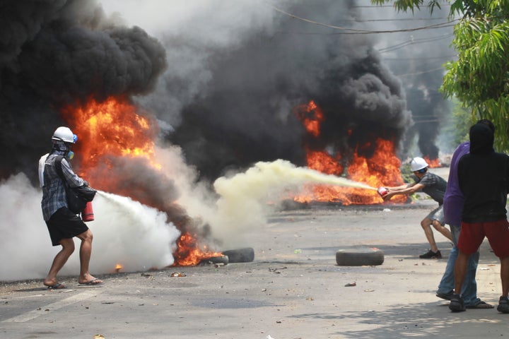 Anti-coup protesters extinguish fires during a protest in Thaketa township Yangon, Myanmar, Saturday, March 27, 2021. 