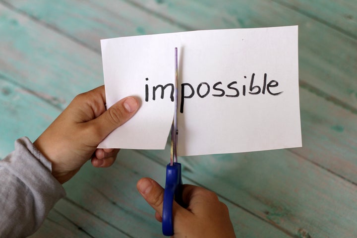 Hands Cutting Paper With Impossible Text