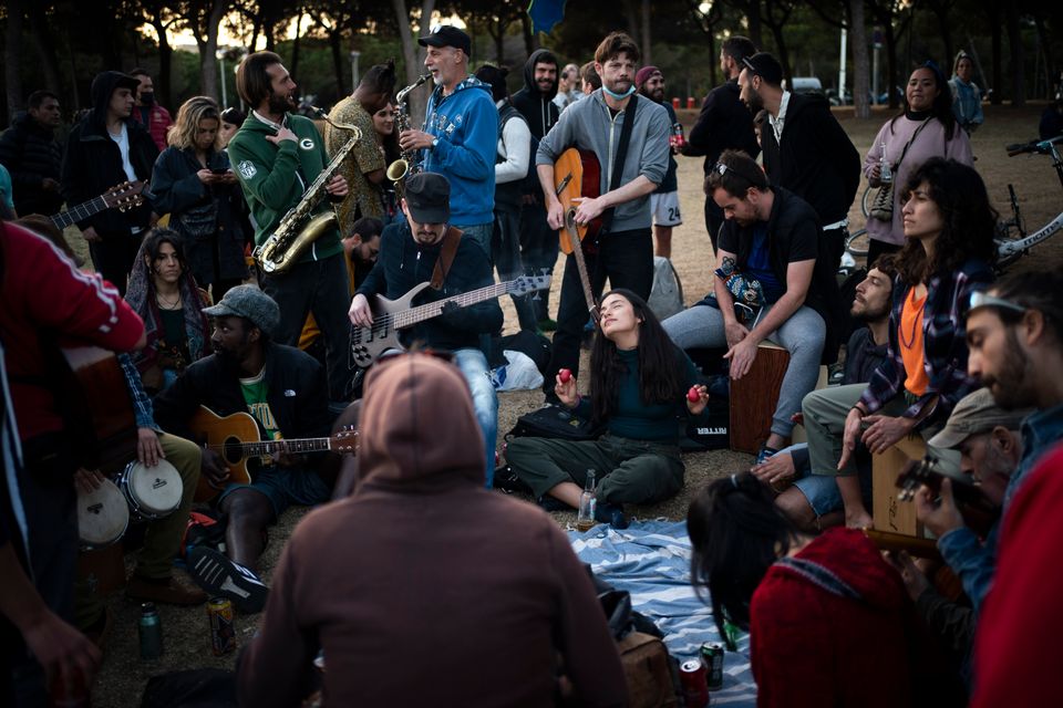 Un grupo de personas toca música sin distancia y pocas mascarillas en un parque de