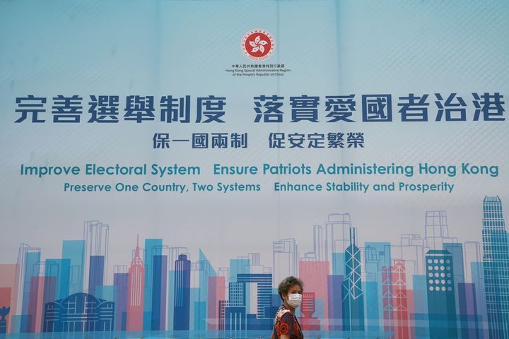 Μία γυναίκα περνάει μπροστά από μία διαφήμιση που προωθεί τις εκλογικές μεταρρυθμίσεις του Χονγκ Κονγκ, μετά την έγκριση του κινεζικού κοινοβουλίου για ένα νέο σχέδιο μεταρρύθμισης του εκλογικού συστήματος,