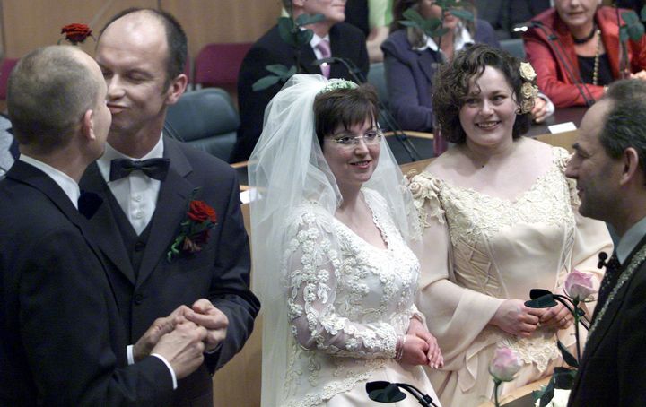 （左から）深夜のアムステルダム市役所で結婚し、キスをするドルフ・パスケルさんとゲルト・カステーさん。彼らに笑顔を向けながら、自分たちが結婚する番を待つヘレネ・ファーセンさんとアンネマリ・フースさん