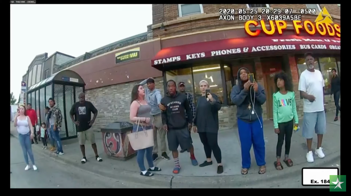 In this still image from the night of George Floyd's arrest, Alyssa Funari can be seen on the far left in white, Kaylynn Gilbert in the center holding a handbag, Darnella Frazier on the right wearing bright blue pants and Judeah Reynolds on the far right in a green shirt.