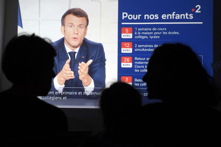 People listen to French president Emmanuel Macron delivering a broadcast speech from the Elysee palace in Paris, in Marseille on March 31, 2021, during a televised address on the new COVID-19 restrictions. (Photo by NICOLAS TUCAT/AFP via Getty Images)