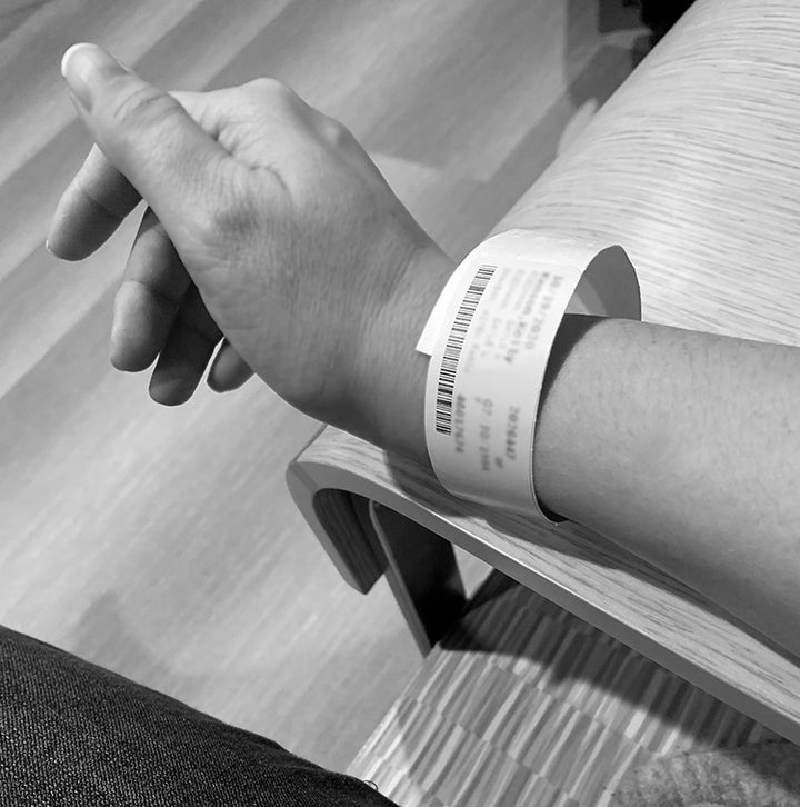 The author staring at her wristband moments before her first MRI. She notes, "I couldn’t stop thinking that they gave me an a