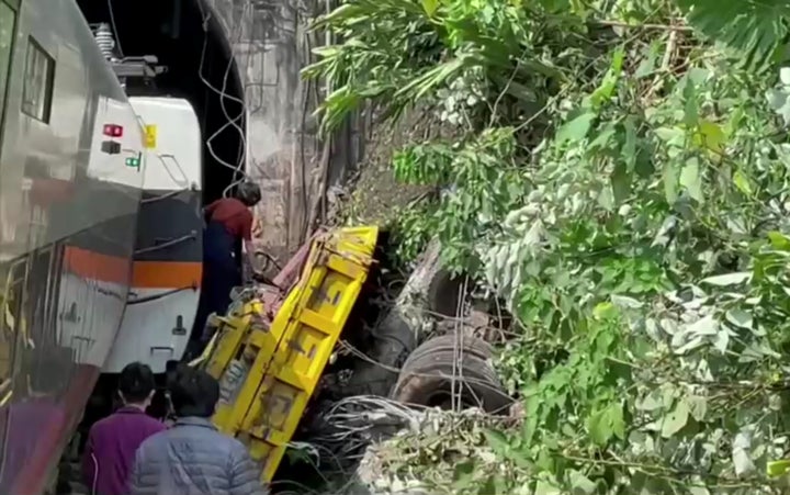 People walk next to a damaged train which derailed in a tunnel north of Hualien, Taiwan in this still image taken from video.