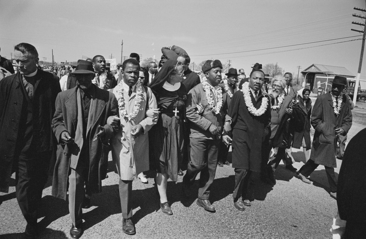 The Rev. Martin Luther King Jr., arm in arm with the Rev. Ralph Abernathy, leads marchers as they begin the march from Brown's Chapel Church in Selma, Alabama, on March 21, 1965. John Lewis, in a light-colored coat, joins the front line.