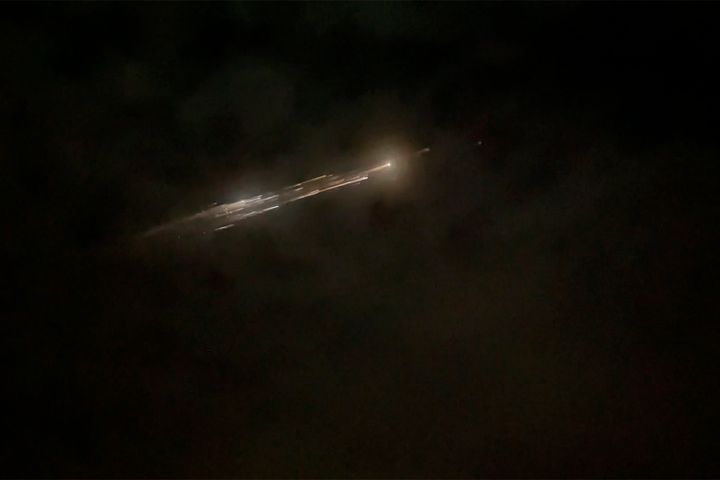In this image taken from video provided by Roman Puzhlyakov, debris from a SpaceX rocket lights up the sky behind clouds over