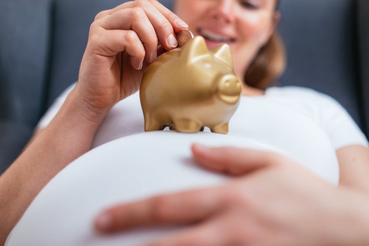 Putting a coin in a gold colored piggy bank at home.