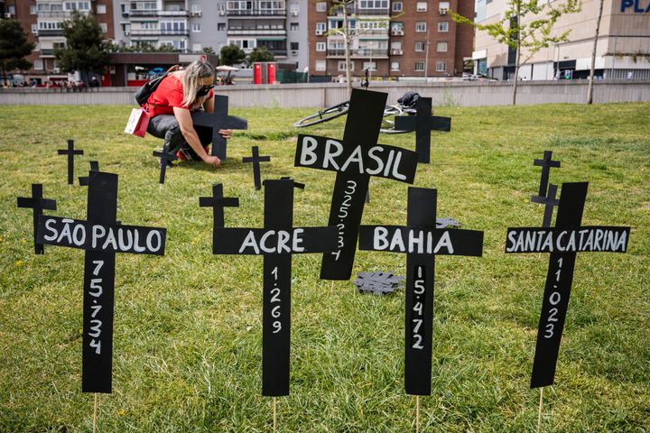 A woman lays a cross in memory of Brazil's Covid victims in the Madrid Rio park