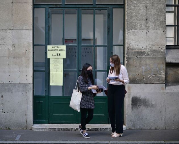 Des élèves portant des masques arrivent pour apprendre le résultat du baccalauréat au lycée Jean-de-La-Fontaine dans le 16e arrondissement de Paris, le 7 juillet 2020.  (Photo by MARTIN BUREAU/AFP via Getty Images)