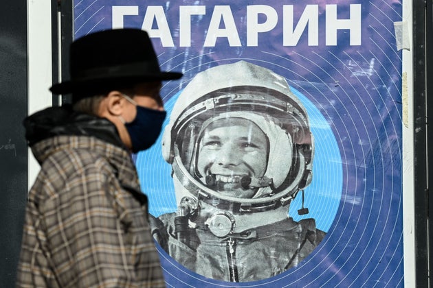 A man, wearing a face mask amid the ongoing Covid-19 disease pandemic, walks past a banner with an image of Soviet cosmonaut Yuri Gagarin in Moscow on April 12, 2021. - Sixty years ago Soviet cosmonaut Yuri Gagarin became the first person in space,  marking a new chapter in the history of space exploration. (Photo by Kirill KUDRYAVTSEV / AFP) (Photo by KIRILL KUDRYAVTSEV/AFP via Getty Images)